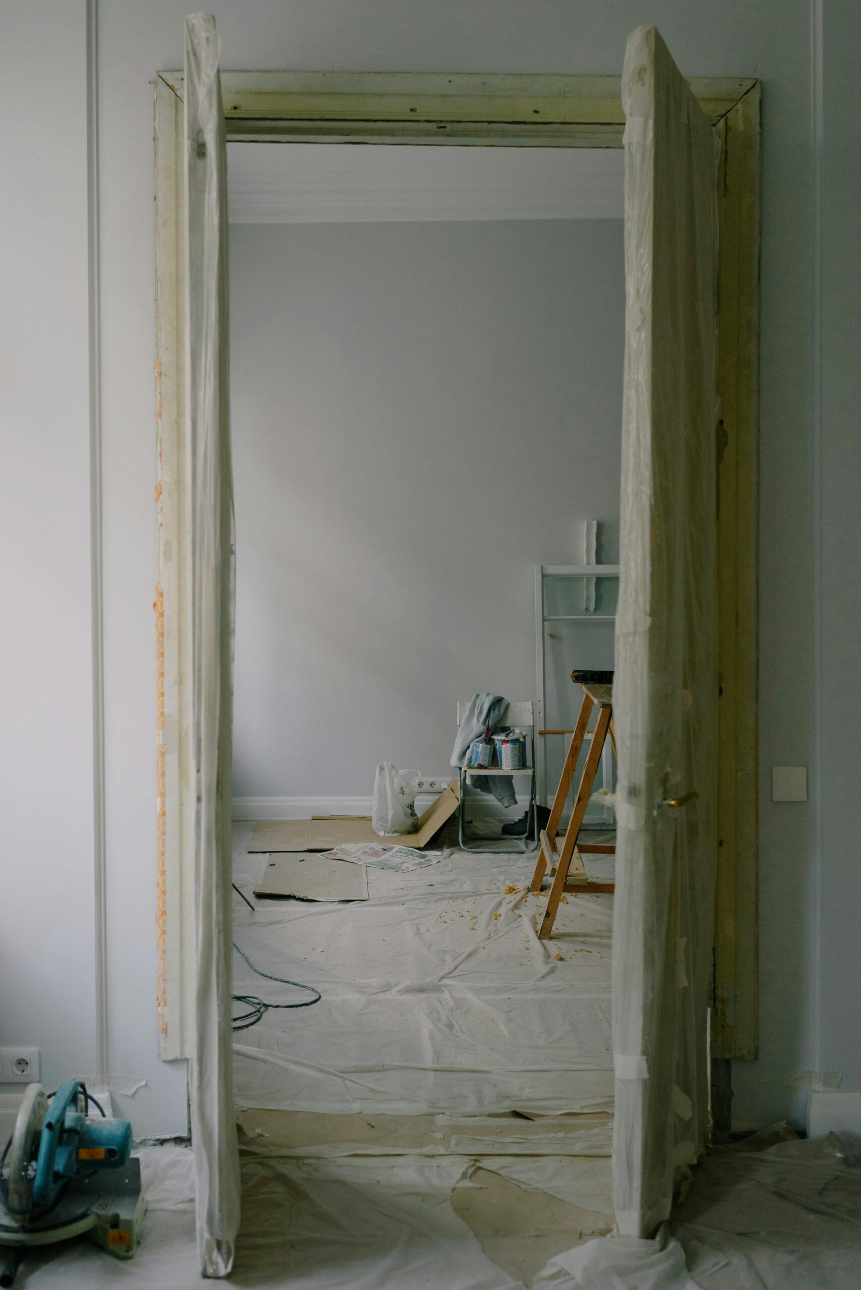 View through an open doorway into a room undergoing renovation with tools and materials scattered.